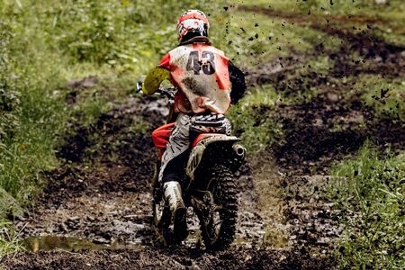 back motocross enduro rider. splashes lumps of dirt