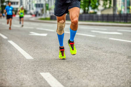 legs runner man in compression socks and knee pads run race down streetの写真素材