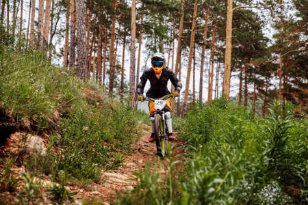downhill rider athlete rides race on trail in pine forest