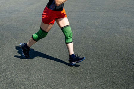 legs elderly female runner in knee pads run raceの写真素材