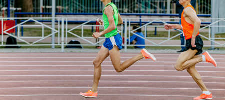 two male athletes runners run at stadium track and field competitionの写真素材