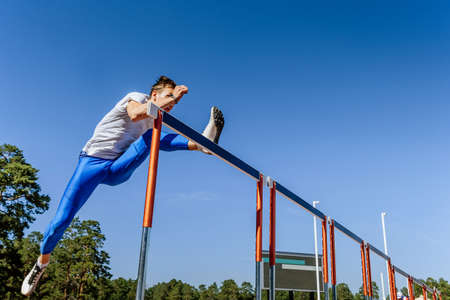 male athlete run 110 meters hurdles at track and field competition