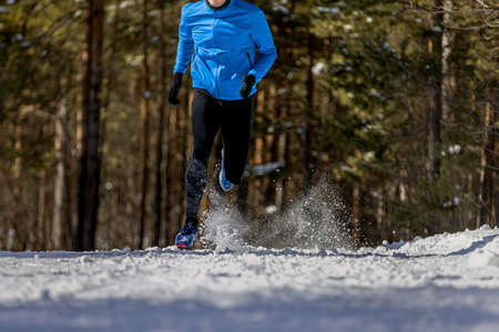 male athlete running on snowy trail in woods