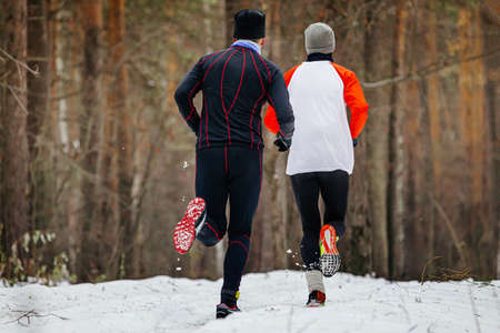 two male runners running winter trail in forestの写真素材