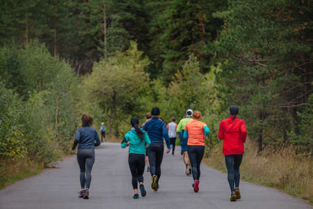 group male and female running in autumn parkの写真素材