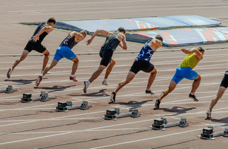 man athletes starting running in 100m sprint race