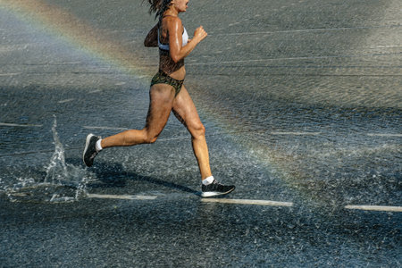 female runner run in water spray and rainbowの写真素材