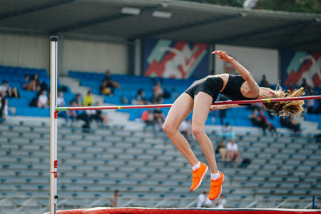 female athlete high jump on background fan standsの写真素材