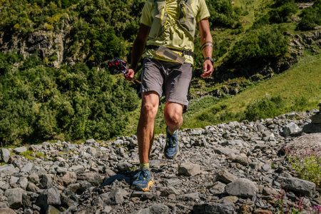 male runner with trekking poles running on rocks