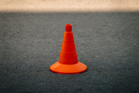 orange traffic cone on dark asphaltの写真素材