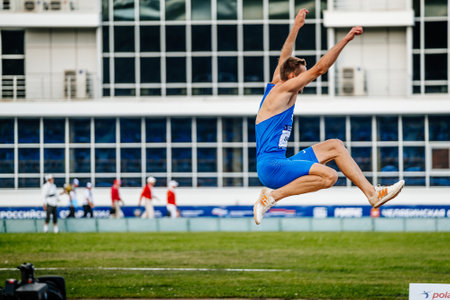 male athlete long jump in competition athletics, spikes shoes for jumping Adidas and tights Nike, sports photoのeditorial素材