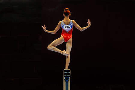 back female gymnast performing exercise balance beam on black background, Spieth balance beam model Soft touch, summer sports gamesのeditorial素材