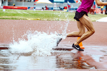 athlete runner running steeplechase in Nike spikes shoes, world championship athletics competition,...