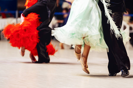 couples dancing viennese waltz in competitive ballroom dancesport, woman is wearing purple and red dress, man on black tail suitの写真素材