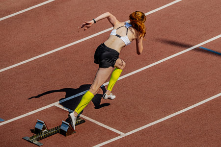 female sprinter start running from starting blocks in summer athletics championshipsの写真素材