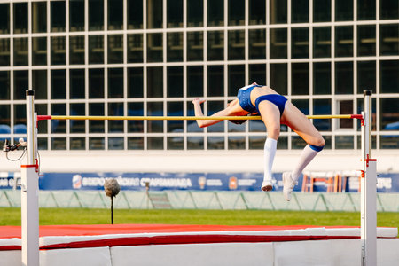 woman athlete going over bar high jump in summer athletics championships, fosbury flop techniqueの写真素材