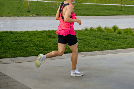 male athlete runner running marathon race in landscape park, summer sports event