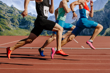 group male athletes running on red track stadium on background mountains and sky. muscles taut, competing fiercelyの写真素材
