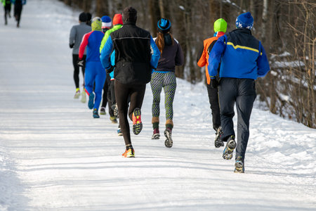 mixed group runners in winter outdoor race or marathon on snow-covered trailの写真素材