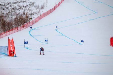 alpine ski athlete racing downhill on snowy ski slope passing finish lineの写真素材