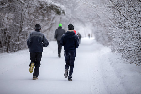 Rear view group of runners running winter marathon in parkの写真素材