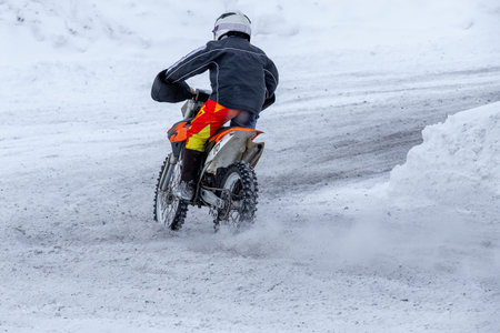Junior motorcyclist riding dirt bike on snowy track during winter racingの写真素材