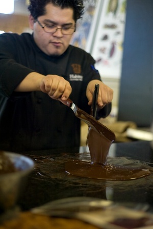 London Ontario, Canada - April 5, 2012. Daniel Cortes of Habitual Chocolate in London Ontario, tempers chocolate on a marble table. The process of temperuing raises and lowers the chocolate temperture creating a stable product that can poured in molds. のeditorial素材