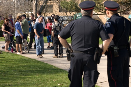 London Ontario, Canada - March 21, 2012. Members of Occupy London hold a press conference in Victoria Park under the watchful eye of London Police. The group read a prepared statement regarding the Ontario Ombudsmans report that finds London  City Councilのeditorial素材