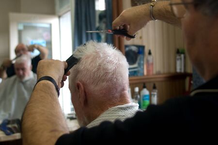 London Ontario, Canada - March 28, 2012. Vincenzo Ioele owner of "Vince's Barber Shop" at 780 Dundas Street in London cuts the hair of George Stovel a regular customer. Ioele opened the shop in 1980 and has been in the same location since then. He has a rのeditorial素材