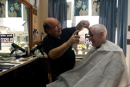 London Ontario, Canada - March 28, 2012. Vincenzo Ioele owner of "Vince's Barber Shop" at 780 Dundas Street in London shares a laugh with George Stovel a regular customer. Ioele opened the shop in 1980 and has been in the same location since then. He has のeditorial素材