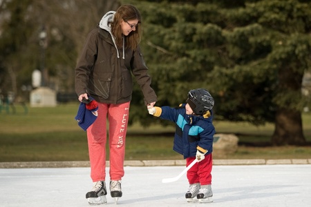 London Ontario, Canada - January 9, 2012. Testing out the new skates. Two year old Bentley Michalak tries out skates he was given at Christmas along with his mother, Karolina Michalak. The two were enjoying unseasonably warm temperatures and bright sun asのeditorial素材