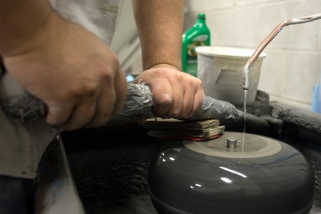 April 26, 2012. Wayne Tuck polishes a curling stone while others wait to be completed. It can take up to 30 minutes to polish a curling rock and is one of the last steps the curling stones go through. Partially completed curling rocks sit waiting to be fiのeditorial素材