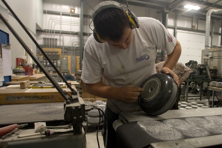 April 26, 2012. Wayne Tuck inspects the running surface on the bottom of a curling rock. Having a consistant running surface will ensure that each rock performs the same way when used in a game. Canada Curling Stone in Komoko Ontario, near London is one oのeditorial素材