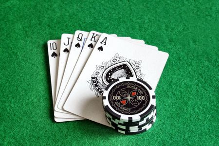 Poker chips with playing cards on green felt