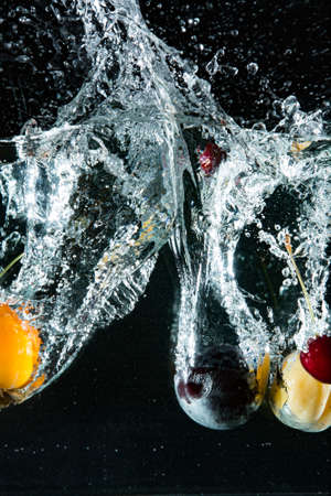 Different fruit in different colors, yelow, red, orange, thrown into water to create splash effect