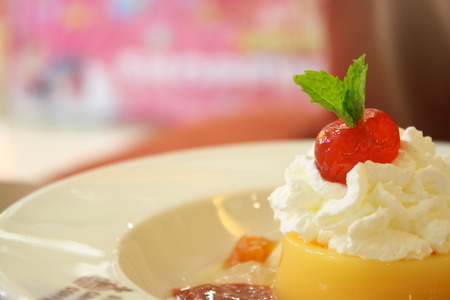 orange pudding with whipping cream and cherryの写真素材
