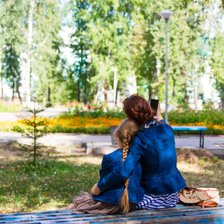 Mother and daughter take a selfie photo in the park in late summer.の写真素材