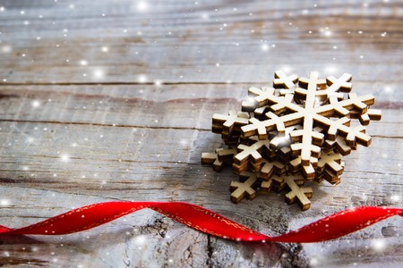 Snowflakes and red ribbon on wooden background. Winter holidays concept.の写真素材