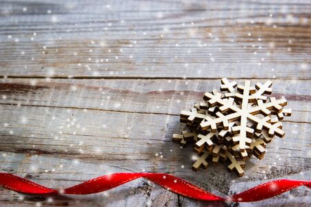 Snowflakes and red ribbon on wooden background. Winter holidays concept.の写真素材