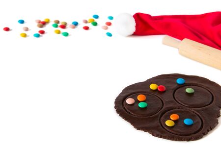 Christmas cookie dough, rolling pin and santa hat on white background.の写真素材