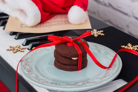 Christmas cookies heap, music sheet and santa's red hat on piano.の写真素材