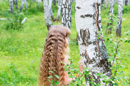 Little blond girl with wavy hair in the forest.の写真素材
