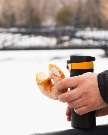 Donuts thermos male hand park outdoors winter coldの写真素材