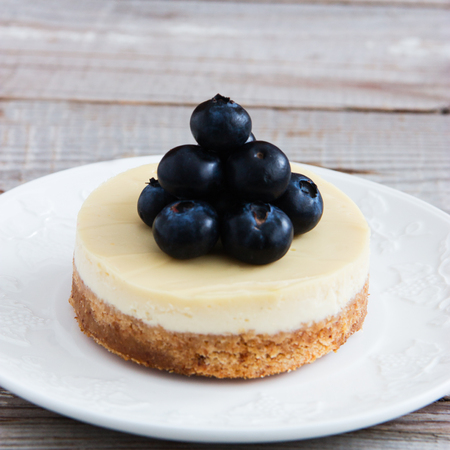 Round cheesecake on white saucer on wooden background.の写真素材