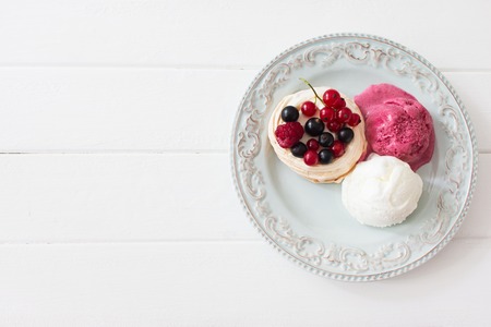 Three dessert ice cream berry pavlova nests kitchen wooden table selective focus.