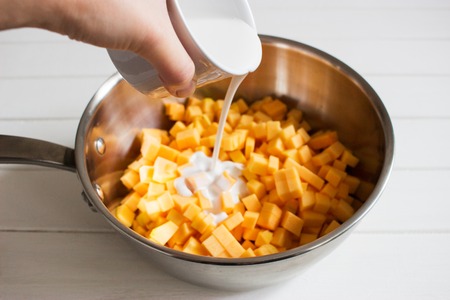 Blurred chopped cubes butternut squash saute pan cream top view.の写真素材