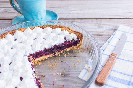 Small meringue covered berry tart wooden table blue ceramics plate.の写真素材