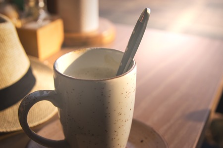Evening latte cup in cafe with fedora hat on wooden table.の写真素材