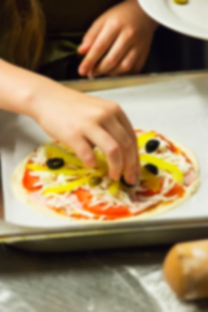 Defocused blur Process pizza cooking dough little girl hands selective focus.の写真素材
