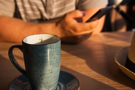 Two mugs latte. Adult men hands smartphone.の写真素材
